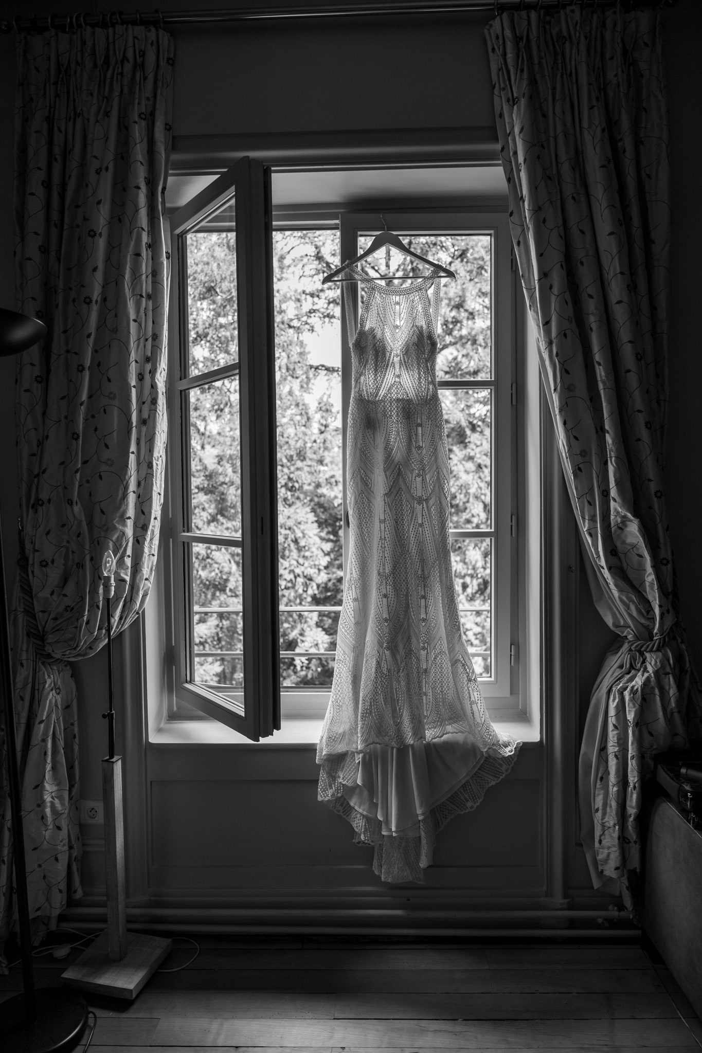 Robe de mariée suspendue à la fenêtre, noir et blanc